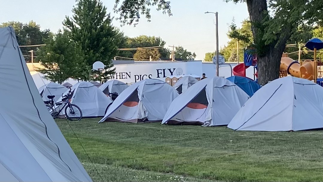 An arrangement of camping tents. Two vestibules are partially open, showing a triangular shape with black, red, and white parts