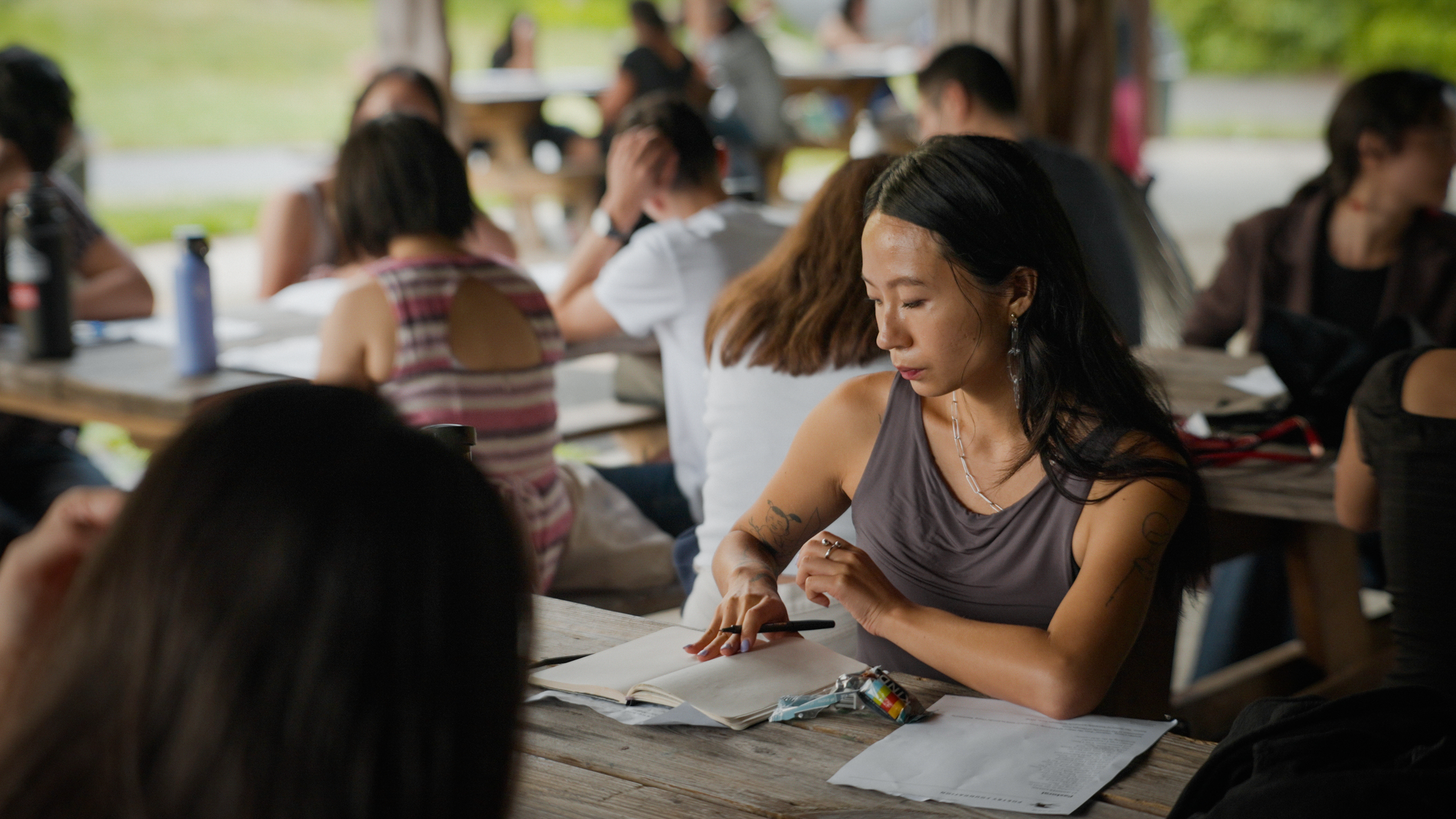 Kundiman Fellows sitting on benches and working on a prompt during the 2023 Retreat.