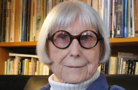 Poet Diane Wakoski in front of a bookshelf.