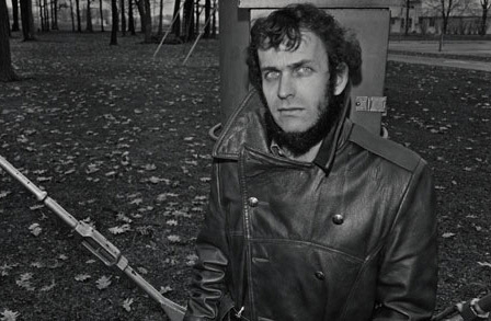 Poet Peter Cooley outdoors surrounded by leaves.