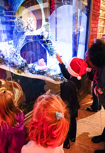 Young boy in a Santa hat pointing to a Merry Makeover display in the Kettering Wintergarden at the Schuster Center
