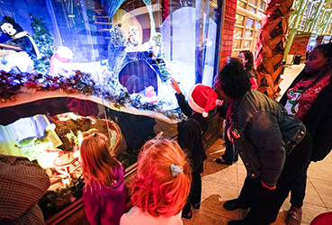 Young boy in a Santa hat pointing to a Merry Makeover display in the Kettering Wintergarden at the Schuster Center
