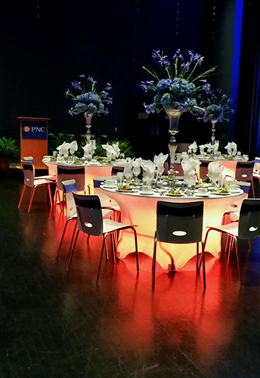 Reception tables set up with dramatic lighting on the Schuster Center stage