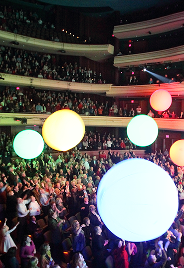 Audience celebrating with glowing light balls at the Schuster Center