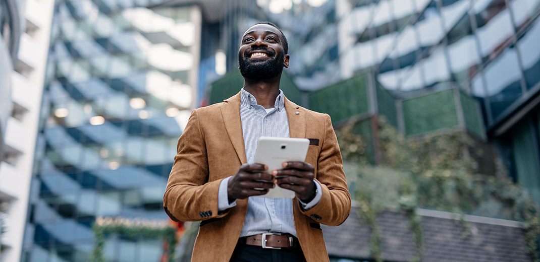 Happy businessperson using tablet in city environment