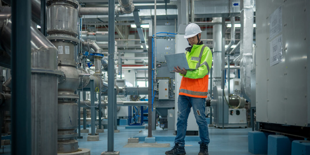 Engineers or technicians working extensive metal piping, HVAC systems, industrial equipment suggesting a controlled, well-maintained environment concept.