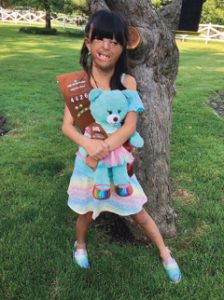 Jing proudly shows off her new bear, with shoes just like her own.