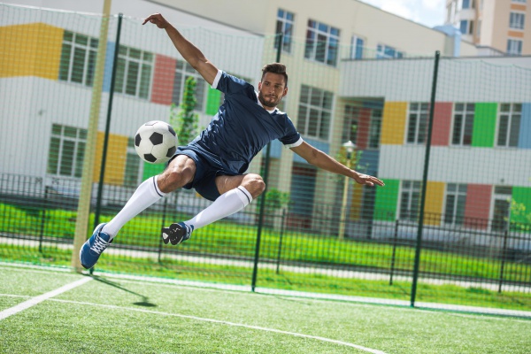 athletic soccer player kicking ball on soccer pitch during match