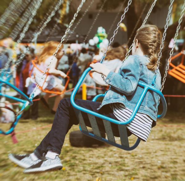 Little girl is riding a carousel in amusement park.