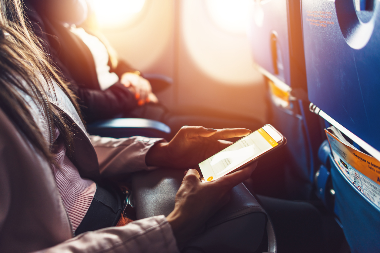 female hands holding smartphone sitting in the airplane with phone