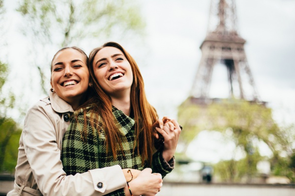 gay couple hugging in front of Eiffel Tower in Paris