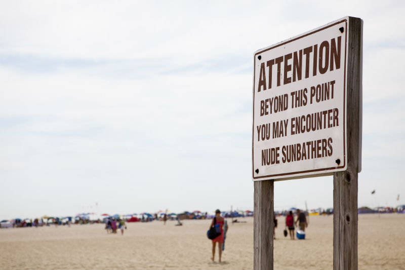 Hundreds of nudist people running into the sea naked