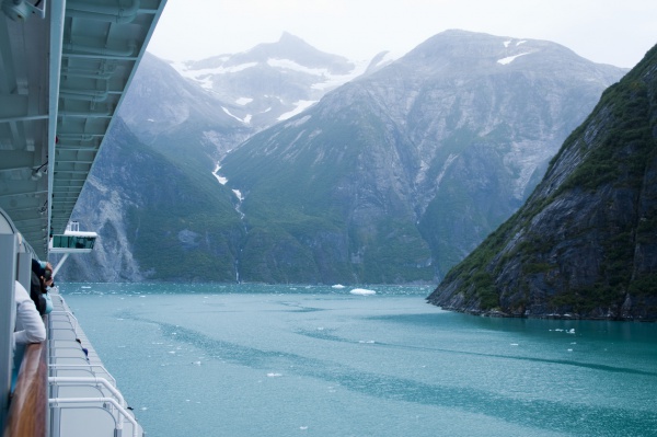 Near vertical mountain slopes carved by glaciers. The cold blue green waters of Tracy Arm Fjord in Alaska as viewed from a cruise ship.