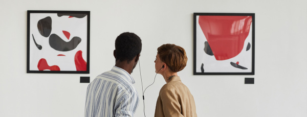 two people looking at art sharing a headphones