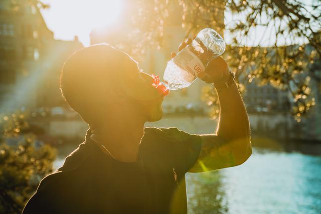 a man drinking from a plastic water bottle