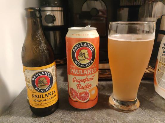 Picture of two Paulaner beverages, a bottle of Münchner Lager on the left, and a can of Grapefruit Radler in the middle. To the right is a tall glass with the mix of both Paulaner beverages.