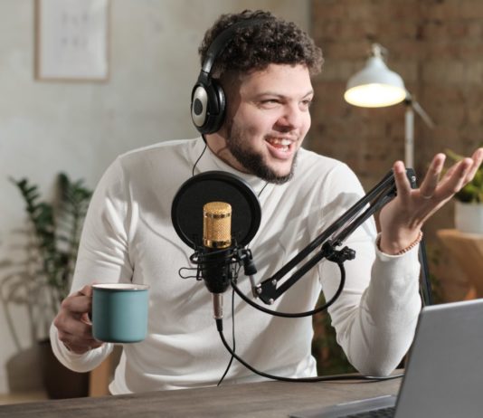 How to Start a Political Podcast Young man in headphones using microphone and recording podcast. Learn how to start your own political podcast & make money