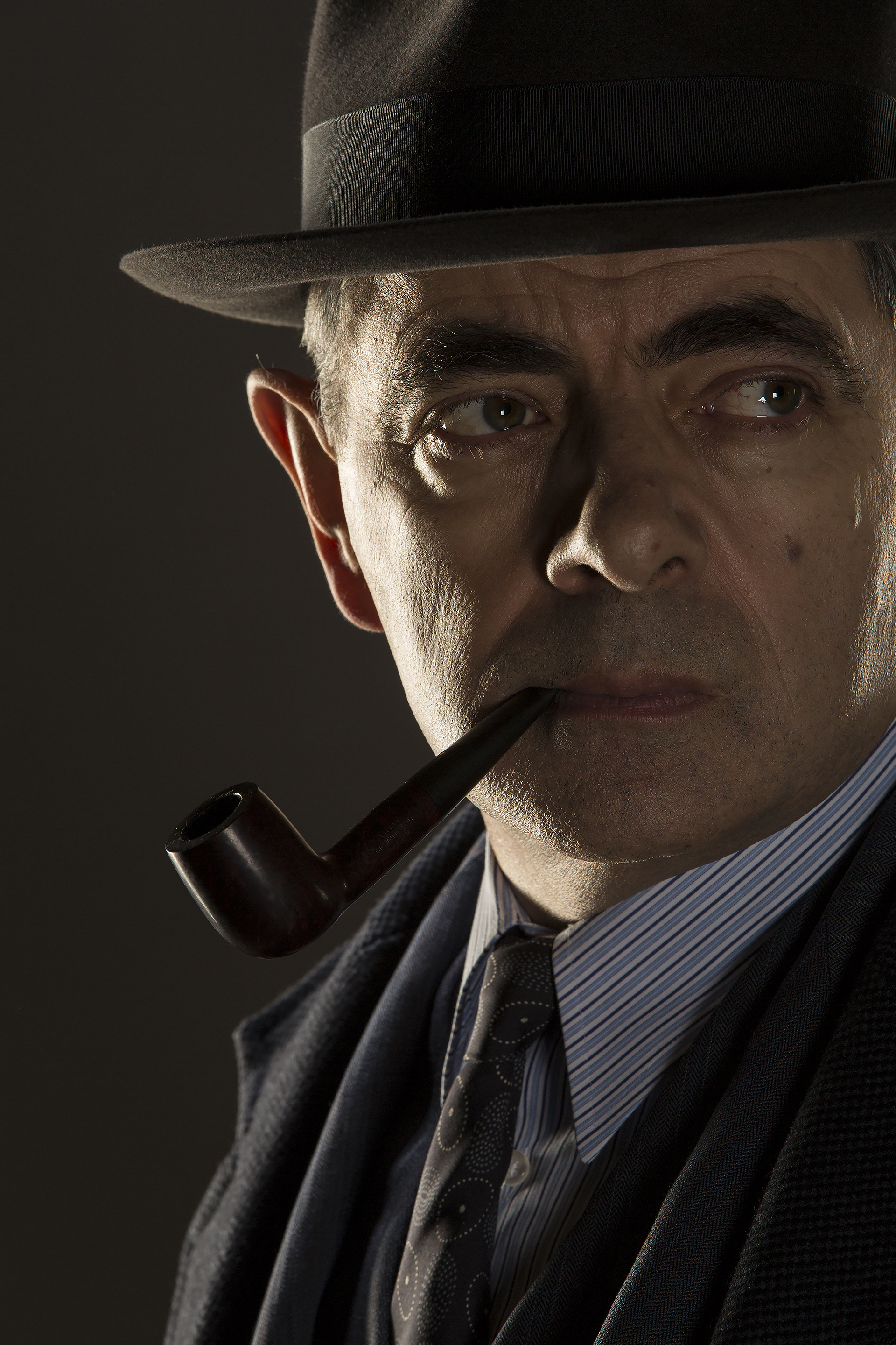 Jules Maigret (Rowan Atkinson) poses with a pipe and fedora.