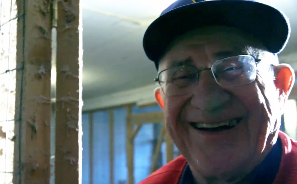 Smiling man wearing hat and glasses.