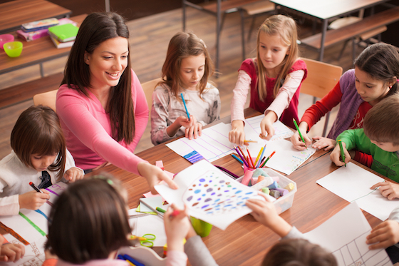 Male teacher helping students on computers. Is teaching recession proof?