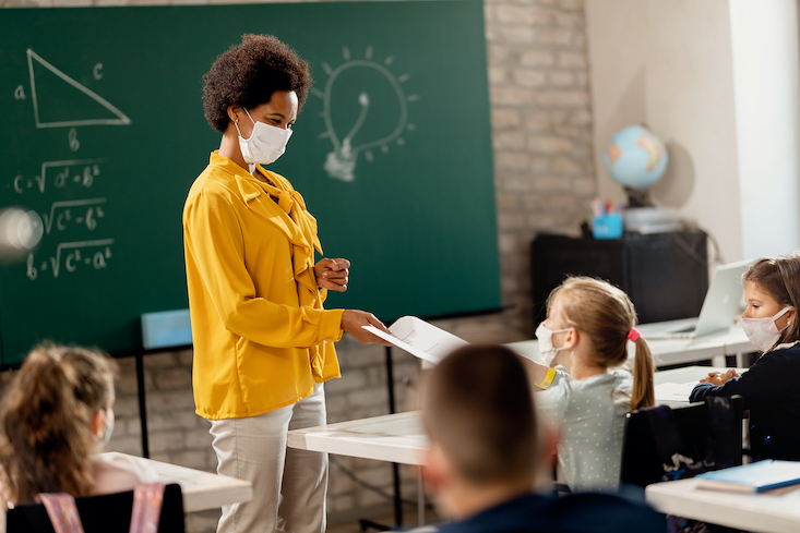 Photo of a teacher with mask on in classroom.