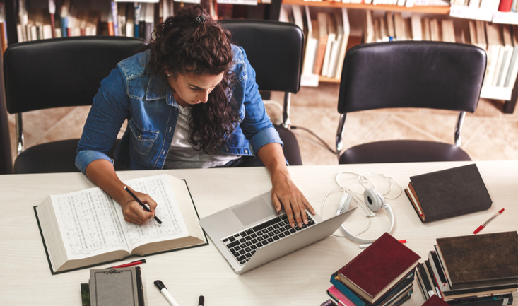female student at a laptop in a library studying