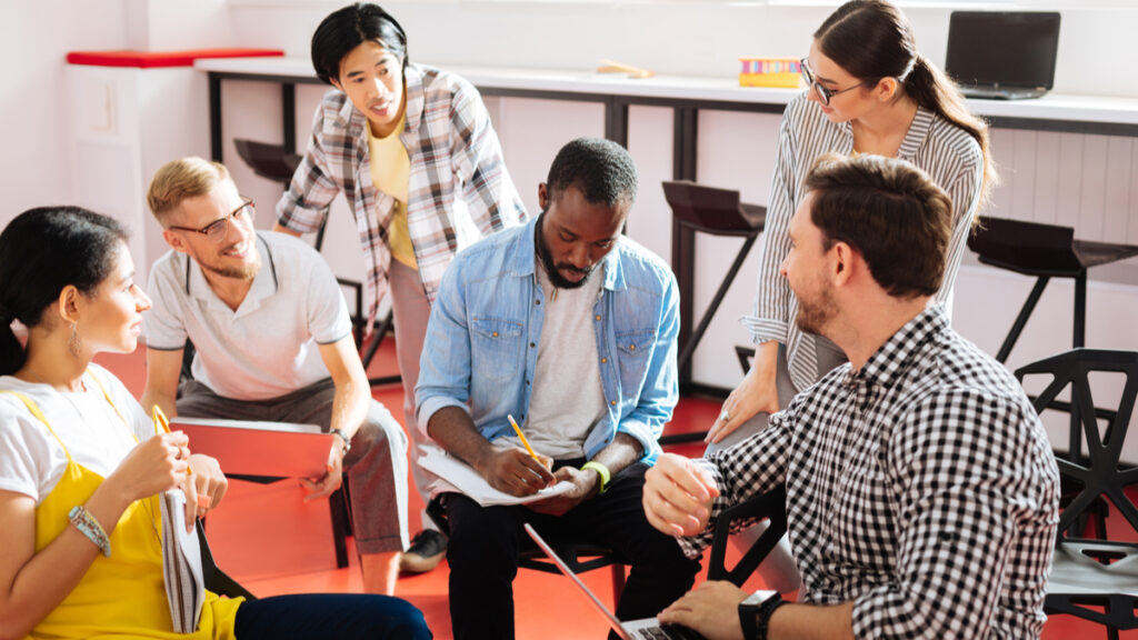 gen z teacher in the middle of a circle of students in the music room